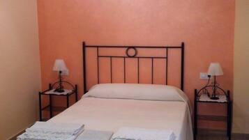 A single bed with a metal frame, two bedside tables with lamps, and a bench at the foot of the bed.