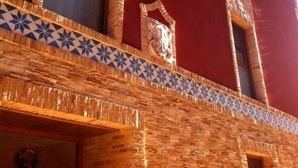 Une façade d’immeuble ornée d’une bordure de carreaux à motifs et de pierres apparentes.