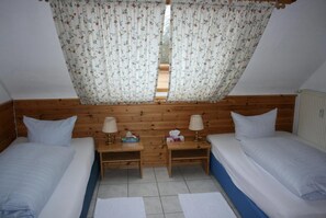 A bedroom with two beds, wooden headboard, white bedding, and a floral curtain. - Hotel Restaurant Anna (Ramstein-Miesenbach)