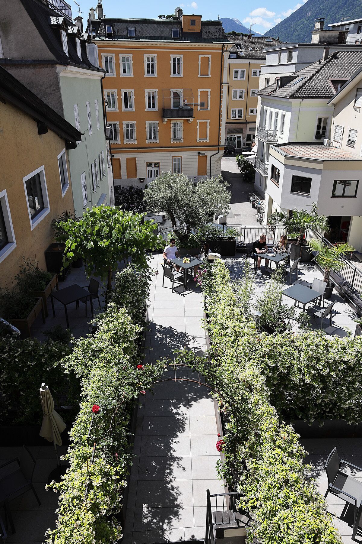 A courtyard with outdoor seating, surrounded by buildings with balconies and windows.