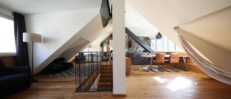 Un vaste loft doté d’un plancher en bois, d’un escalier, d’un coin repas et d’un hamac.