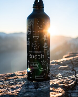 A water bottle with various icons and the text "Residence Rosch" on a textured surface with a blurred background.