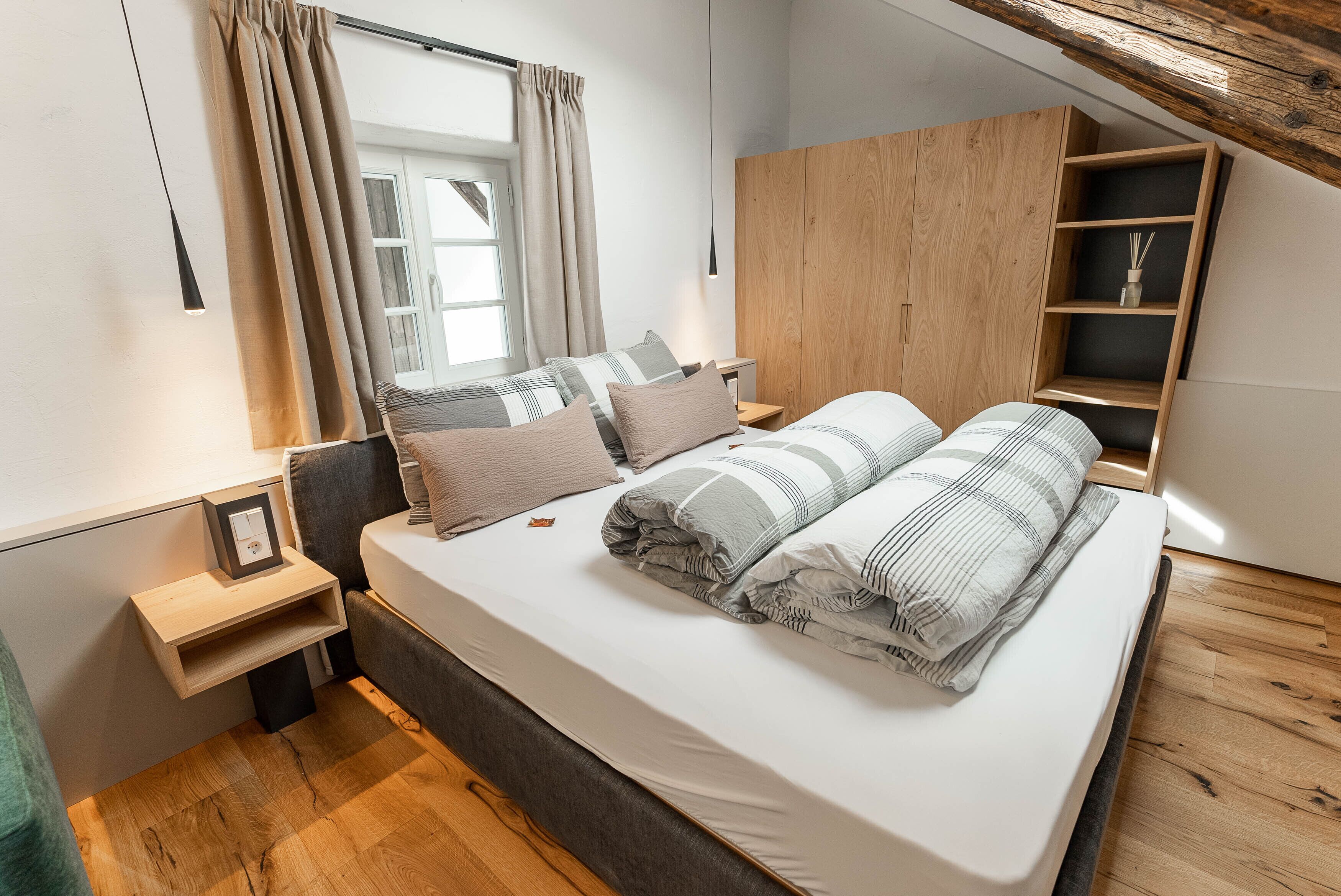 Una camera da letto con un letto, comodini, un'armadio in legno e una finestra con tende.
