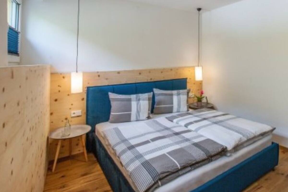 A bedroom with a wooden headboard, a bed with striped bedding, a bedside table, and a nightstand.