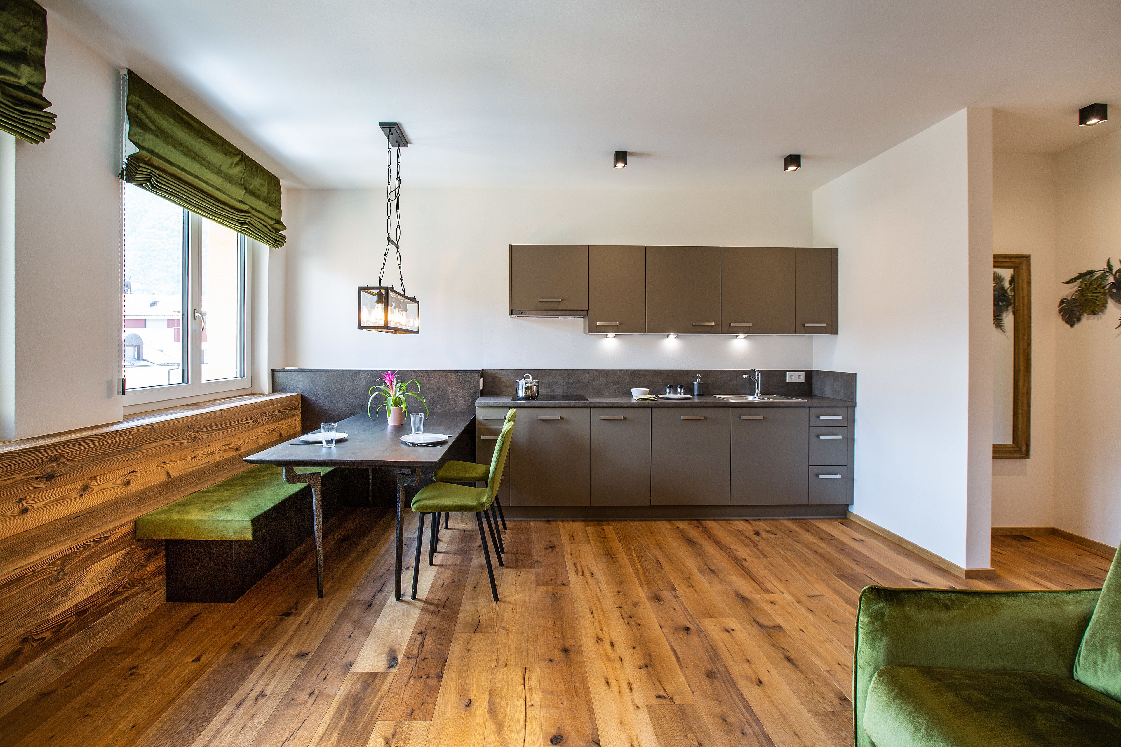 Una cocina moderna con suelo de madera, una mesa de comedor con sillas y un banco.