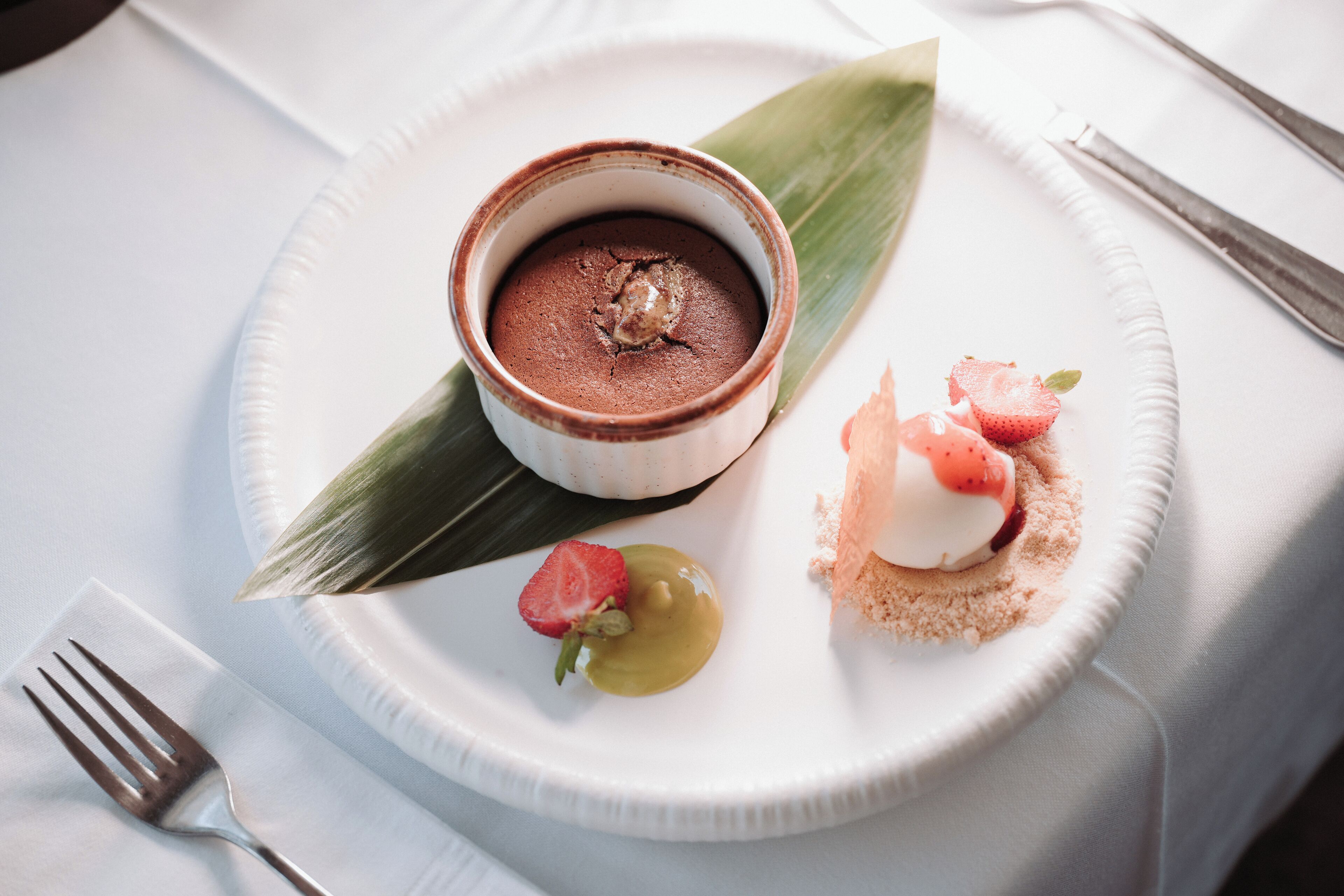 A dessert plate with chocolate mousse, strawberries, and a dollop of cream on a white plate.