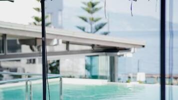 Un área junto a la piscina con sillones de descanso y una pérgola.