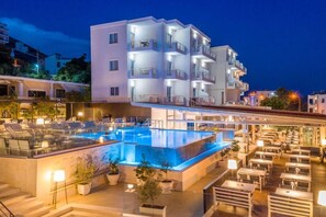 A hotel with a rooftop pool, outdoor seating area, and multiple balconies. - Hotel Agimi (Sarandë)