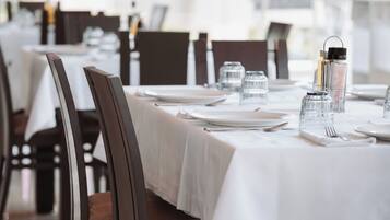 Un restaurante con mesas dispuestas para comer, que presenta sillas de madera oscura y manteles blancos.