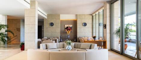 Een moderne lobby met een centraal zithoek, grote ramen en een moderne lamp.