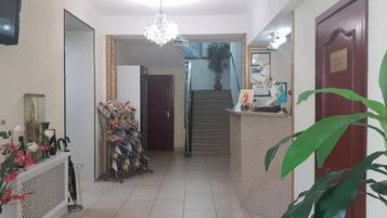 Un pasillo con mostrador de recepción, una escalera y un televisor montado en la pared.