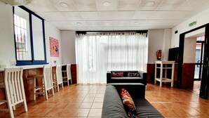 Una hall d'albergo con un divano, sedie, un tavolino e una finestra con tende.