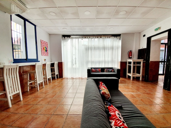 A hotel lobby with a sofa, chairs, a small table, and a window with curtains.