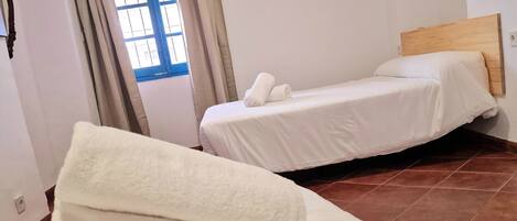 Una habitación de hotel con dos camas, una ventana con cortinas y un equipo de aire acondicionado en la pared.