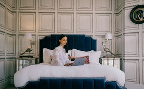 A bed with a dark headboard, white bedding, and a laptop on it. There are two bedside tables with lamps and decorative items. - Rowan Tree Your Apartment (Bristol)