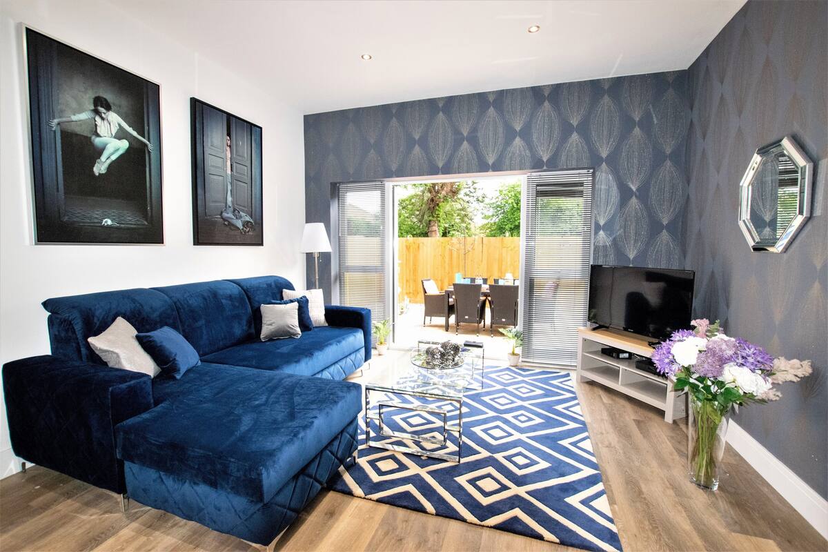 A modern living room with a blue sofa, a glass coffee table, and a TV stand.