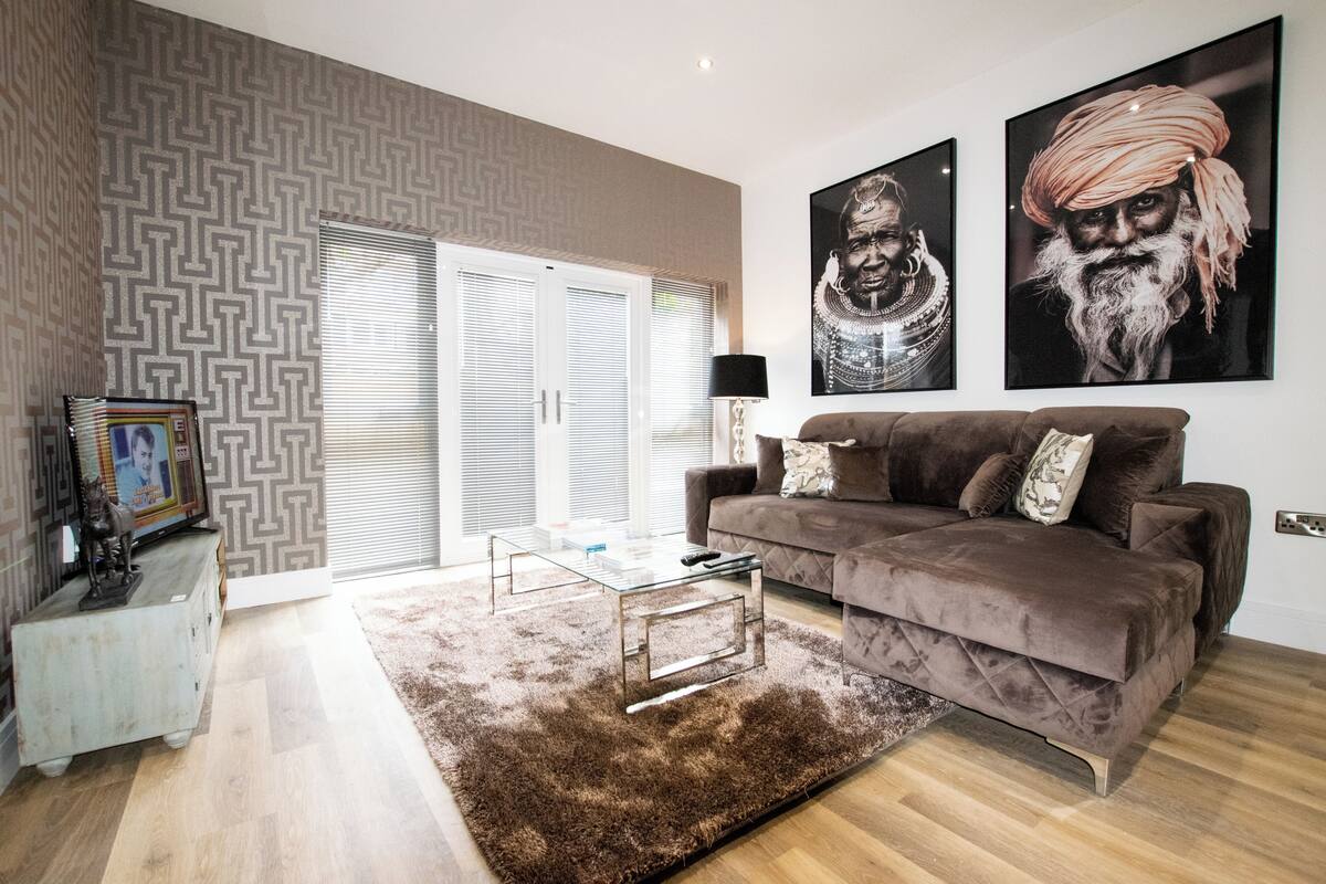 A living room with a brown sofa, a glass coffee table, and a patterned rug.