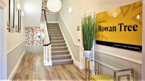 A modern interior with a staircase, a welcome sign, and a potted plant. - Rowan Tree Your Apartment (Bristol)