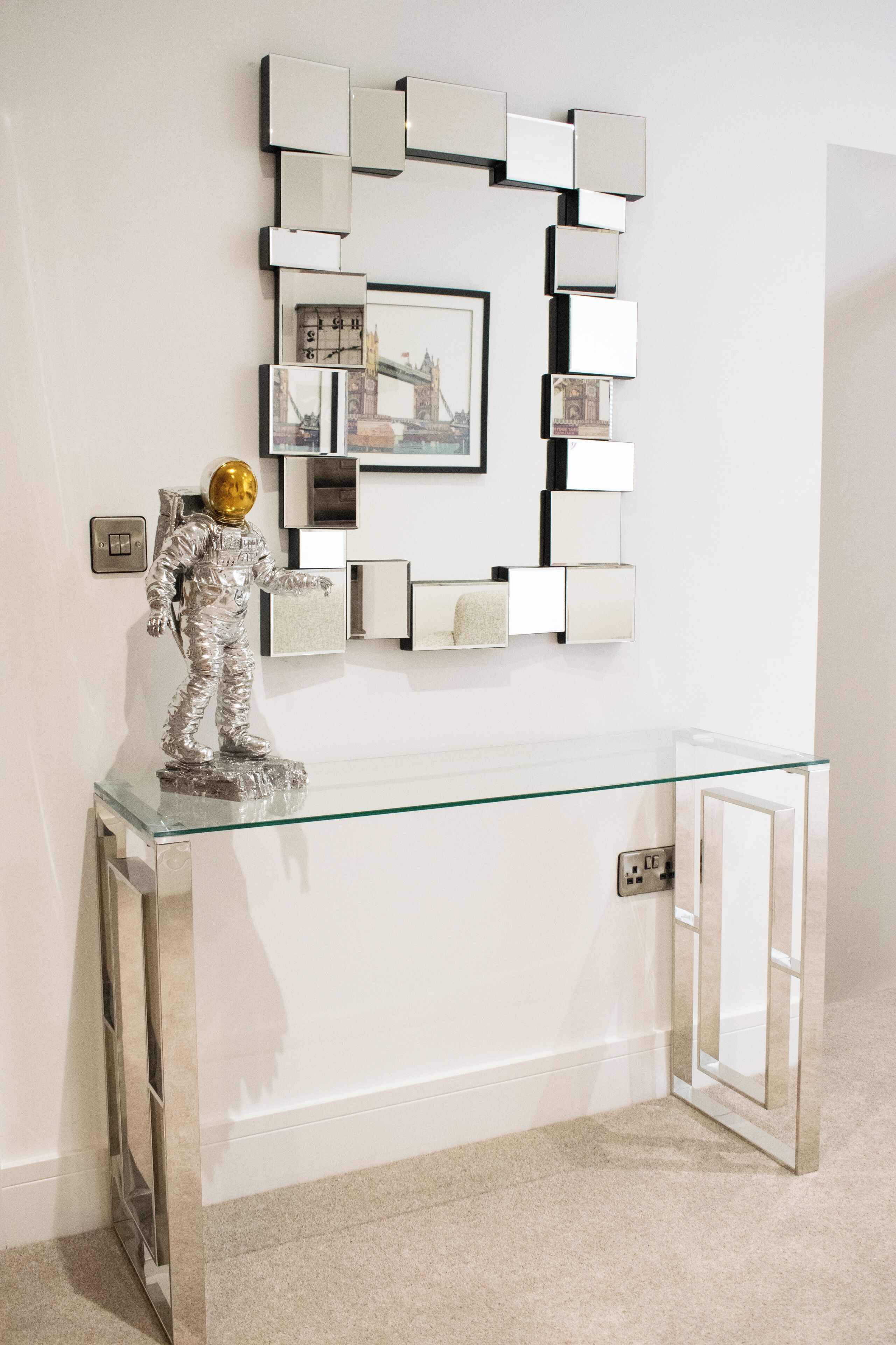 A modern bathroom with a glass vanity, a wall-mounted mirror, and a decorative astronaut figure.