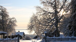 Een besneeuwd landschap met een houten hek en gebouwen op de achtergrond.