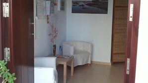 Habitació amb llit, taula petita, cadira, aire condicionat fixat a la paret, quadre amb marc i porta amb tranca.