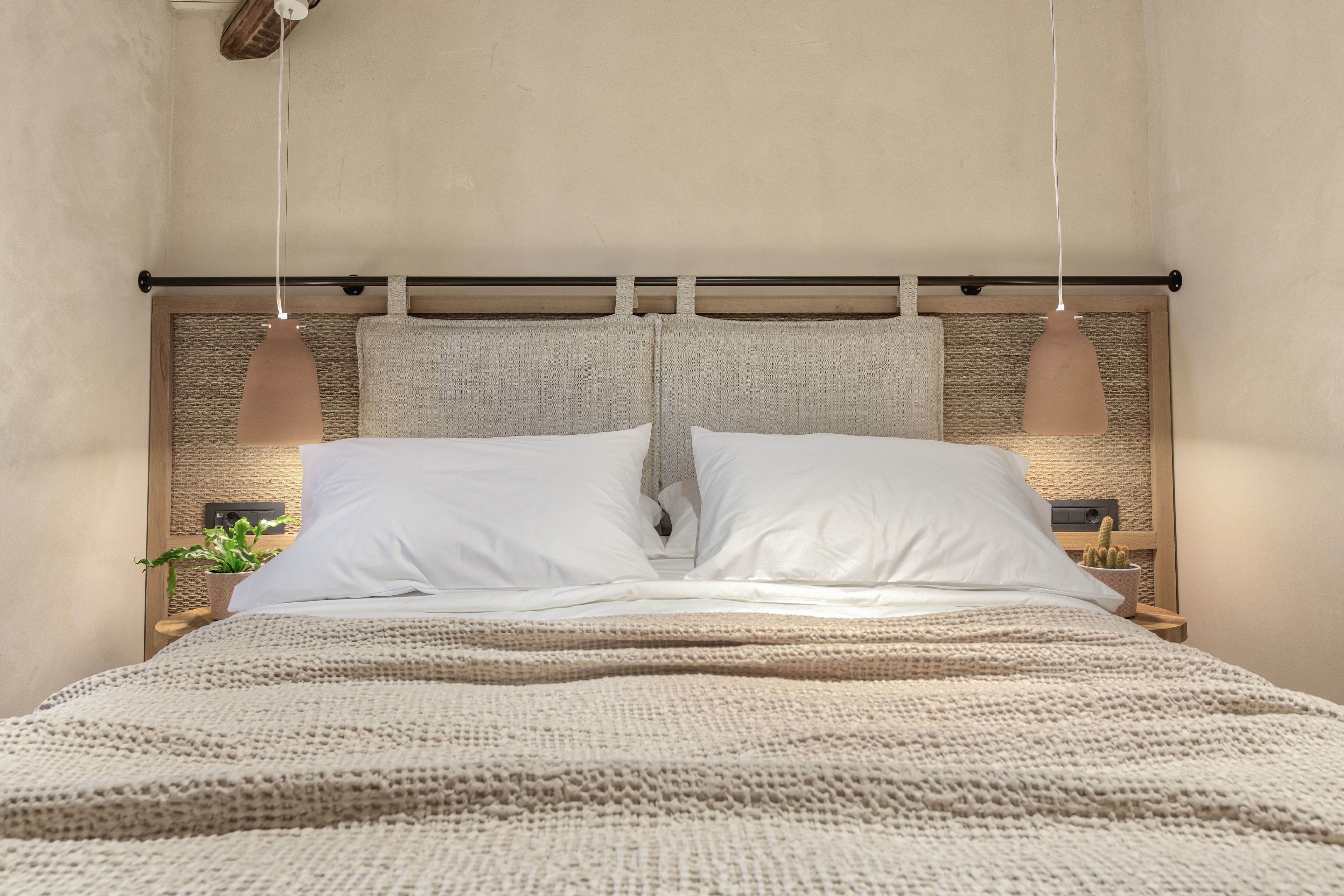 A bed with a textured headboard, two bedside tables with lamps, and a knitted blanket.
