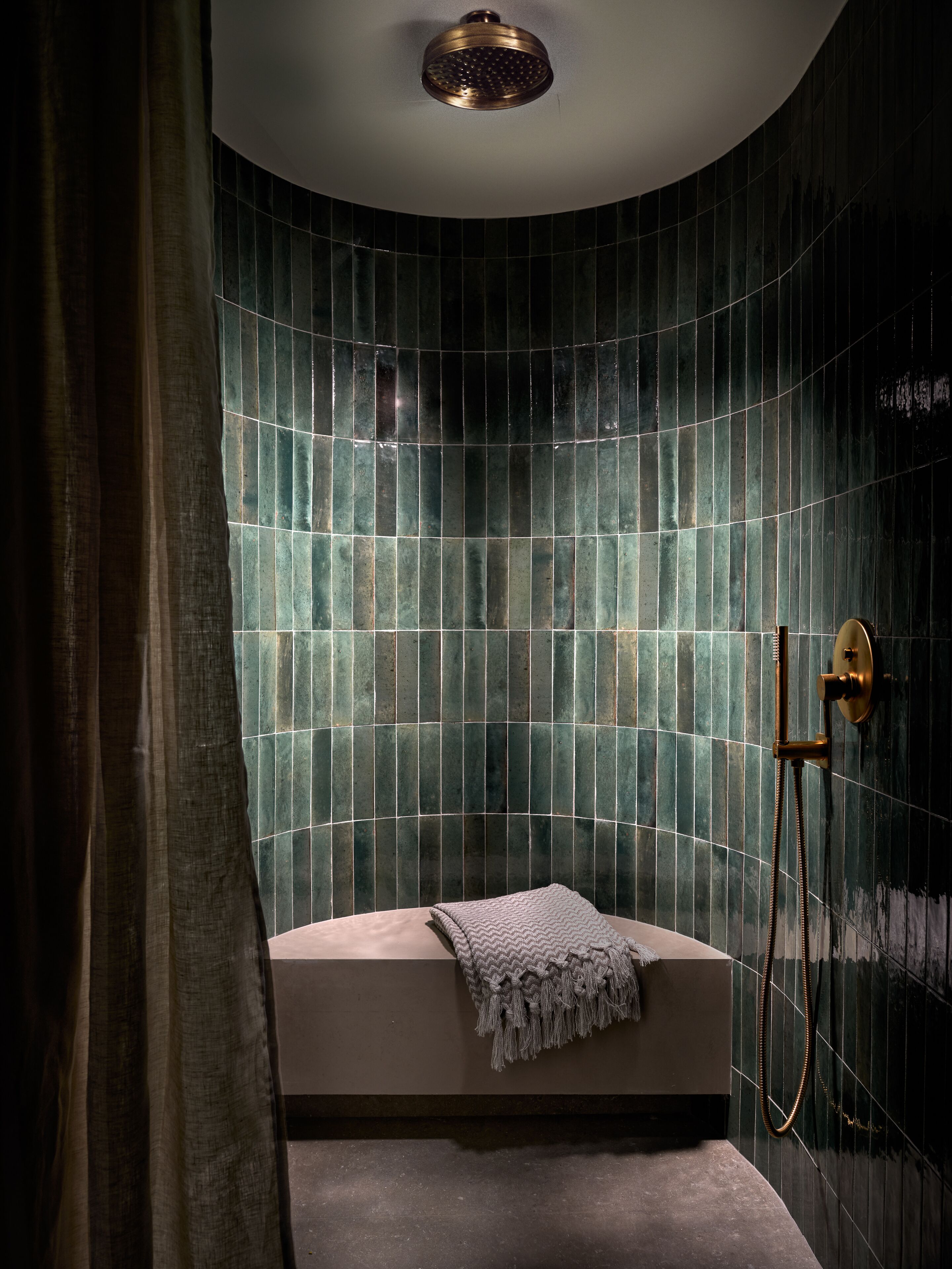 A modern bathroom with a curved shower wall, a bathtub, and a handheld showerhead.