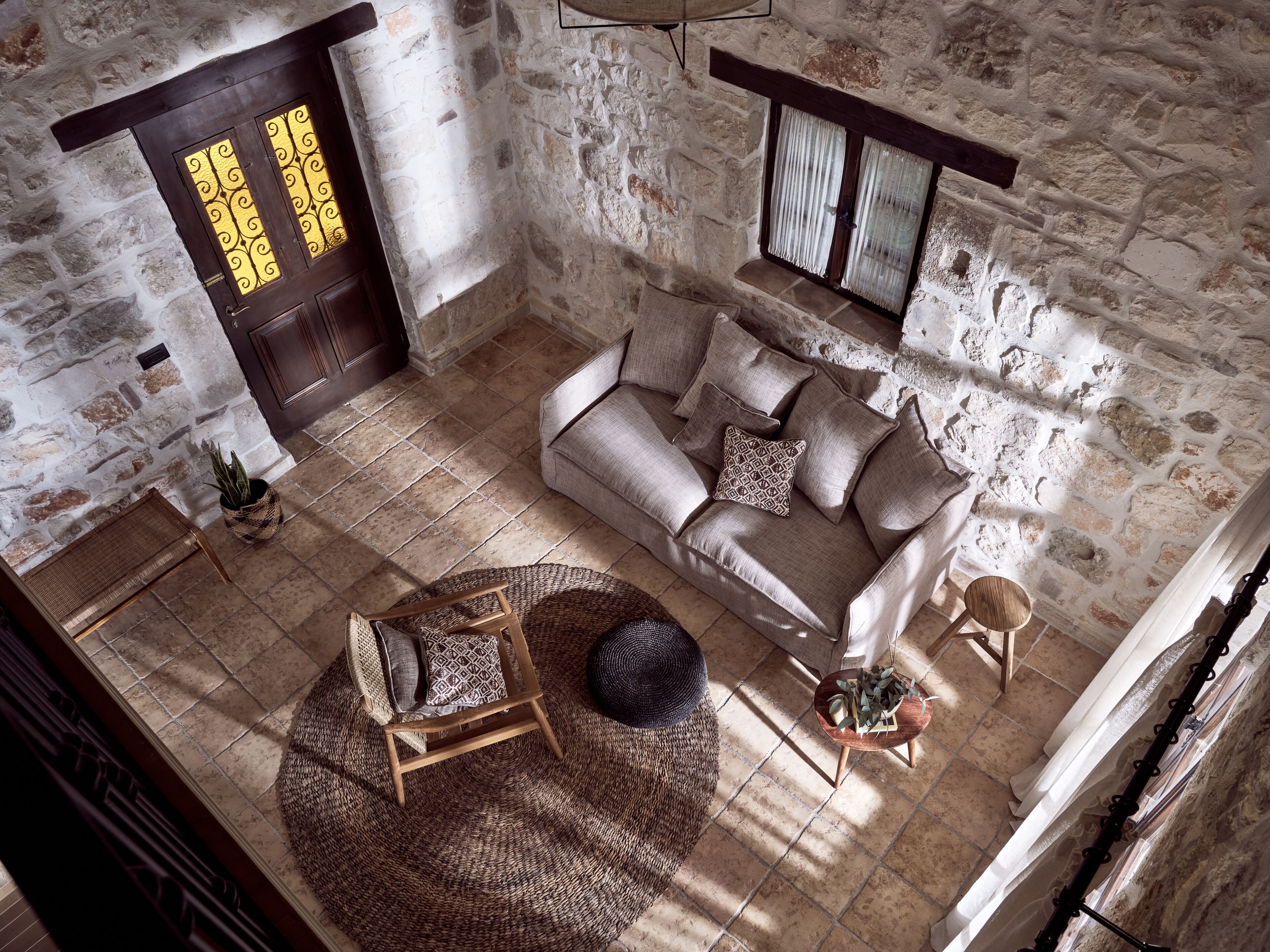 A stone-walled room with a sofa, a small round table, and a chair.