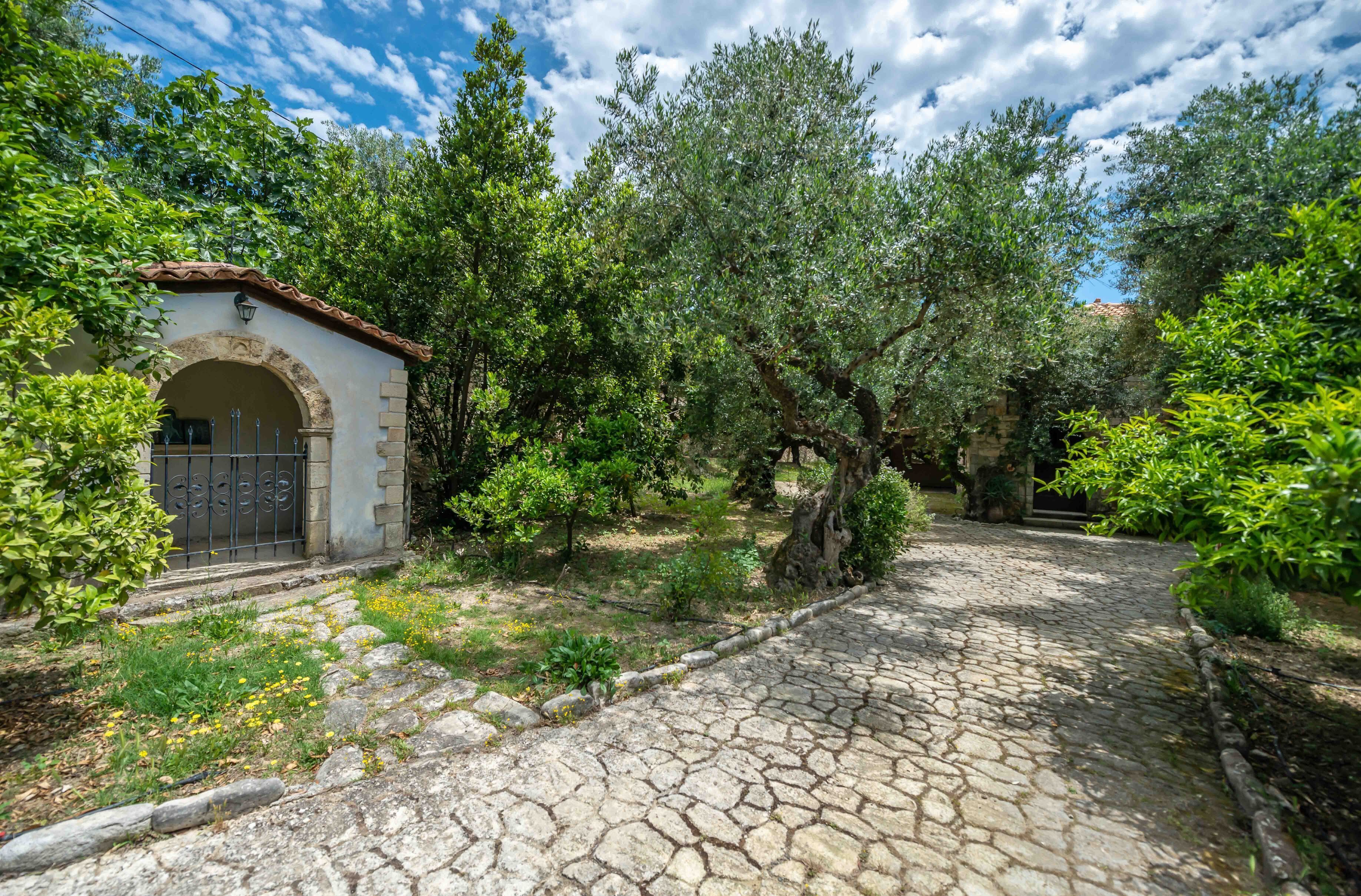 A stone pathway leading to a white building with an arched entrance and a metal gate.