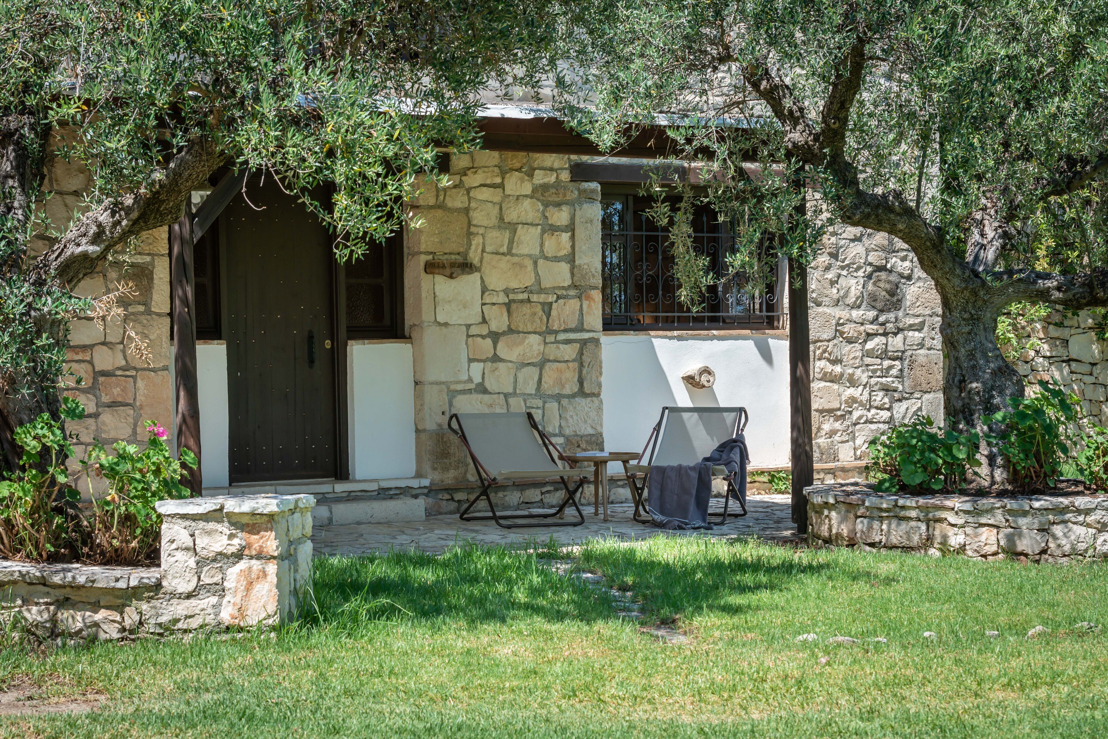 A stone building with a dark door, a small table, and two chairs outside.