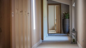 Un pasillo con puertas de madera, una cesta de mimbre con plantas y un farol.