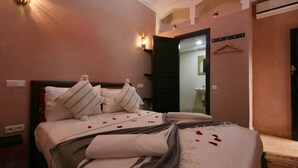 A hotel room with a bed, a nightstand, a mirror, and a wall-mounted light fixture. - Riad Elite (Marrakech)