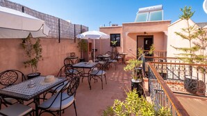 An outdoor patio with tables and chairs, a white umbrella, and potted plants. - Riad Elite (Marrakech)