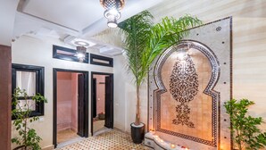 A hallway with a tiled wall, a potted plant, and a hanging light fixture. - Riad Elite (Marrakech)