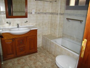 A bathroom with a wooden vanity, a sink, a mirror, a toilet, and a shower enclosure. - Webooking Konstantinos Villa (Argaka)