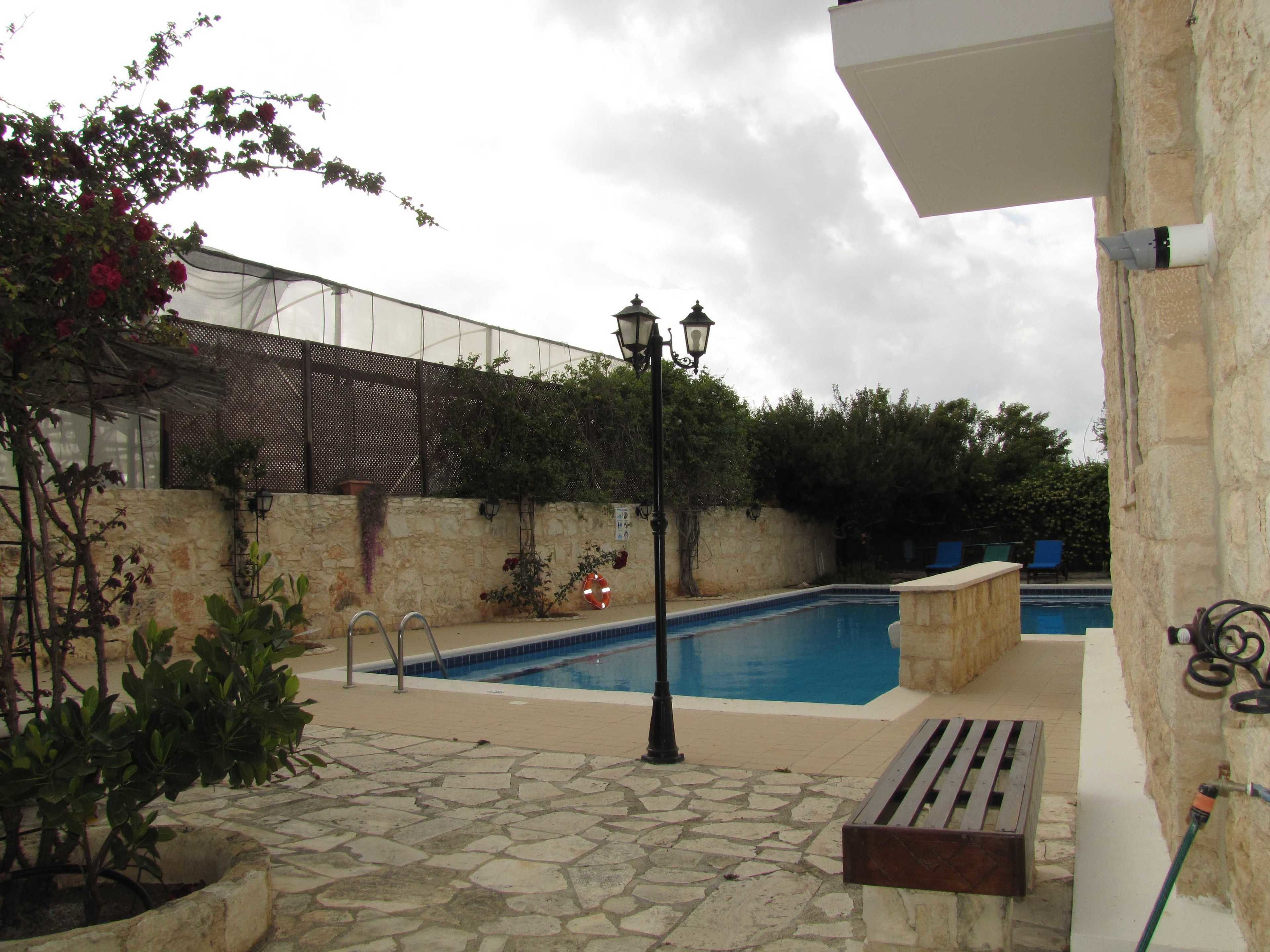 A pool area with stone flooring, a bench, and a lamp post.