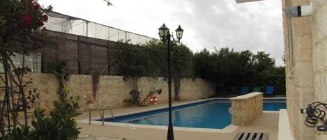 A pool area with stone flooring, a bench, and a lamp post.