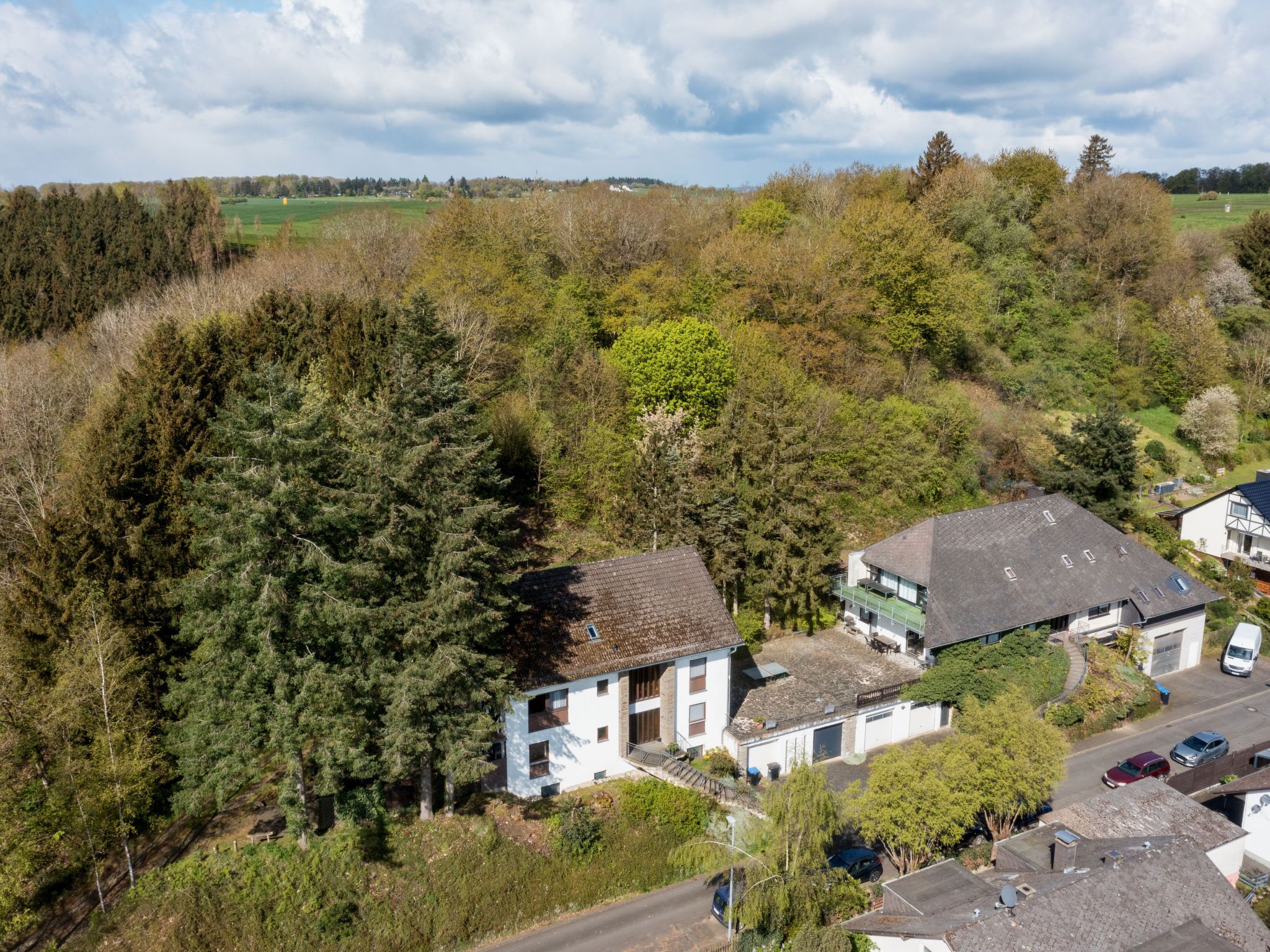 Een woonwijk met huizen, omringd door dichte bossen en een heldere lucht.