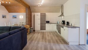 A modern kitchen with white cabinets, a built-in oven, and a microwave. There is a dining area with a sofa and chairs. - Eifelnatur (Haus 2) by Interhome (Immerath)