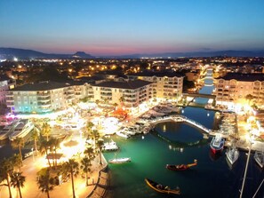 A marina with boats, a bridge, and a hotel with multiple floors and balconies.