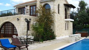 Un edificio de piedra con piscina, mobiliario exterior y una escalera que lleva a un balcón.