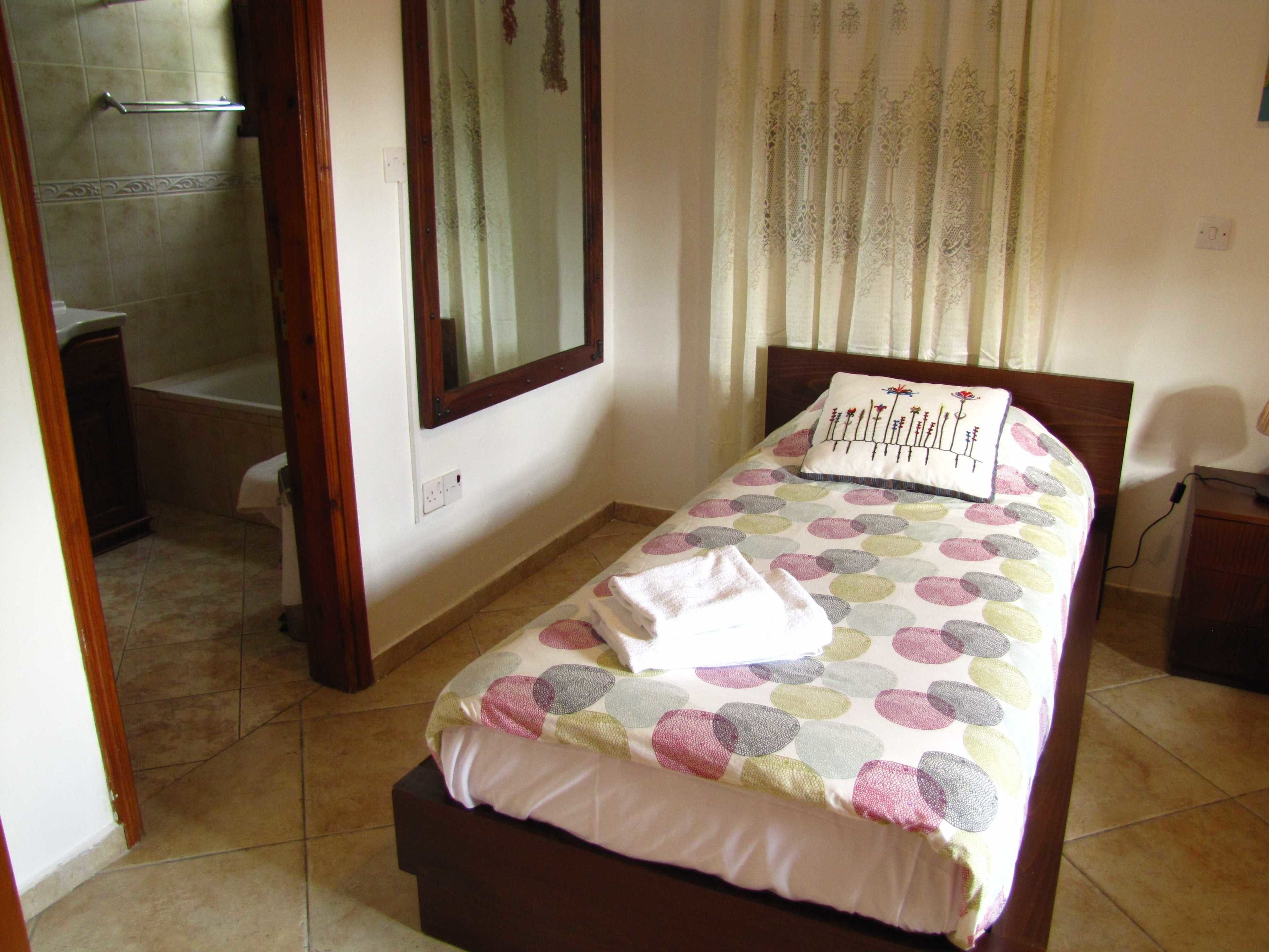 A bedroom with a bed, a window, a shower, and a toilet.