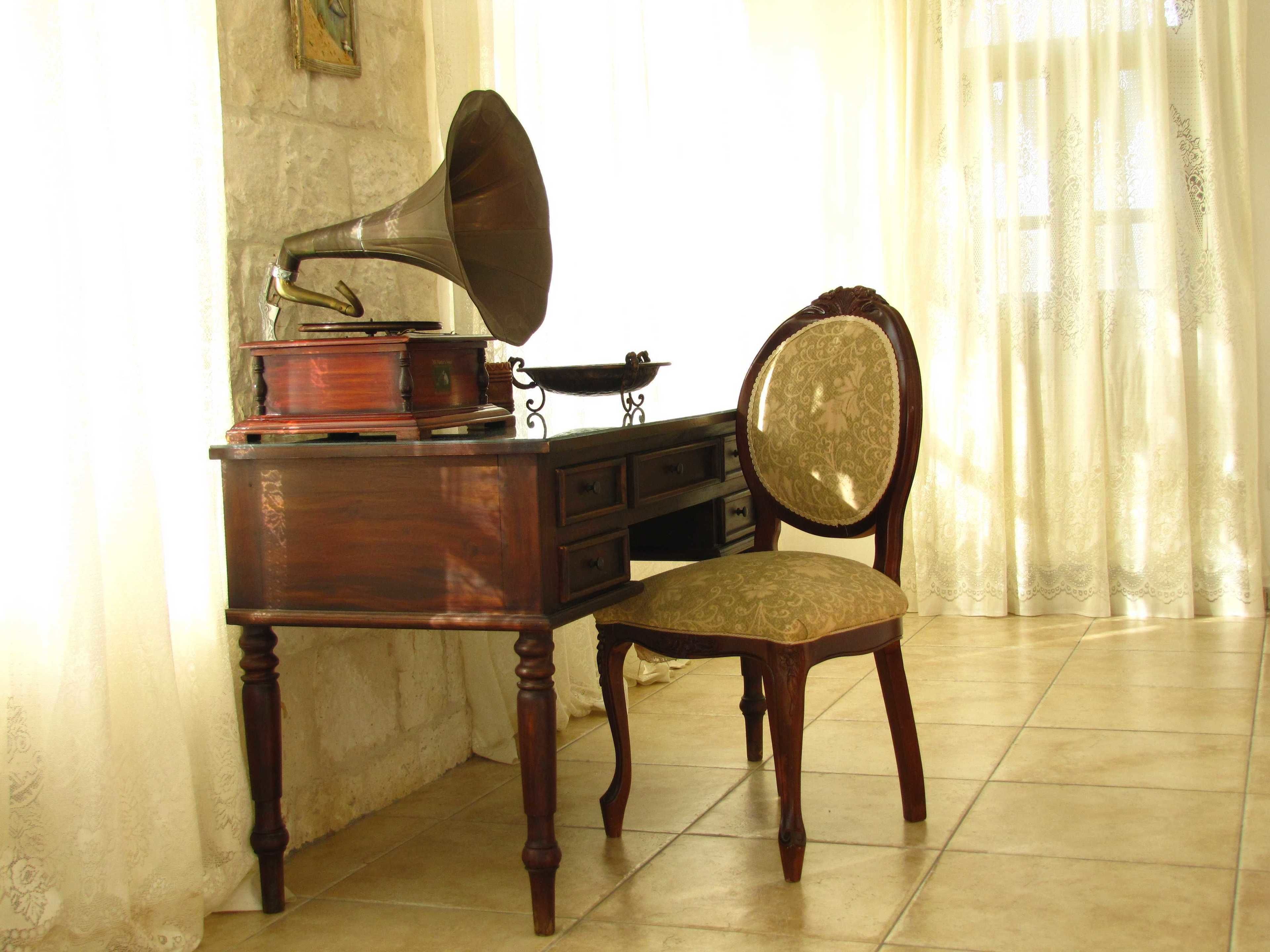A vintage gramophone on a wooden desk with a chair.