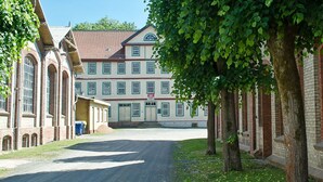 A building with a red brick facade, large windows, and a covered entrance. - Campinghotel Eulenburg - Hostel (Osterode am Harz)