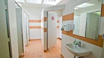 A modern bathroom with a skylight, a no-smoking sign, a hand dryer, and a sink with a mirror.