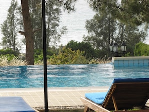A swimming pool with a view of the sea, surrounded by trees and a lamp post. - Webooking Knossos Villa (Argaka)