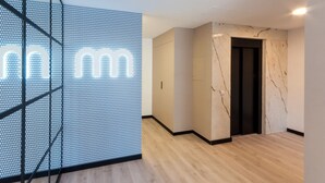 Un intérieur moderne avec un motif géométrique sur un mur, un mur d’accent en marbre et un plancher en bois.