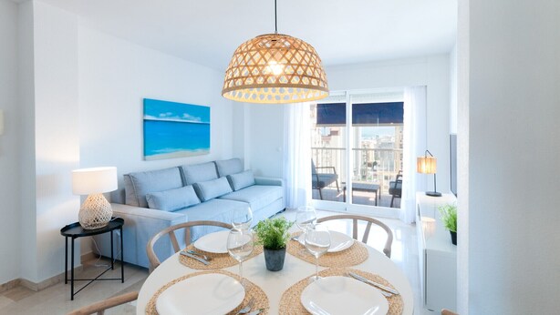 Un coin repas avec une table ronde dressée pour quatre personnes, un canapé, une lampe et un tableau accroché au mur.