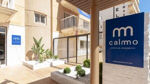 Un immeuble avec une enseigne indiquant « Calmo Apartments » et une entrée fermée par un portail.