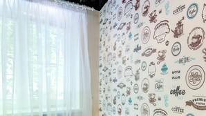Ein Zimmer mit Glastisch, Erdbeeren, einem weißen Vorhang und einer Wand mit Kaffeemotiven.